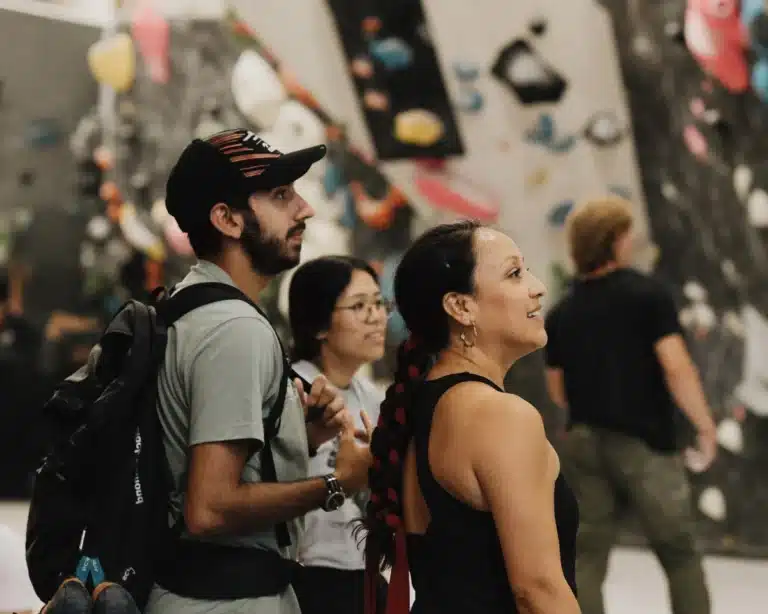 Climbers at Climb So iLL at the Steel Shop look on as climbers scale the bouldering wall.